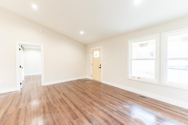 spare room with hardwood / wood-style flooring and lofted ceiling