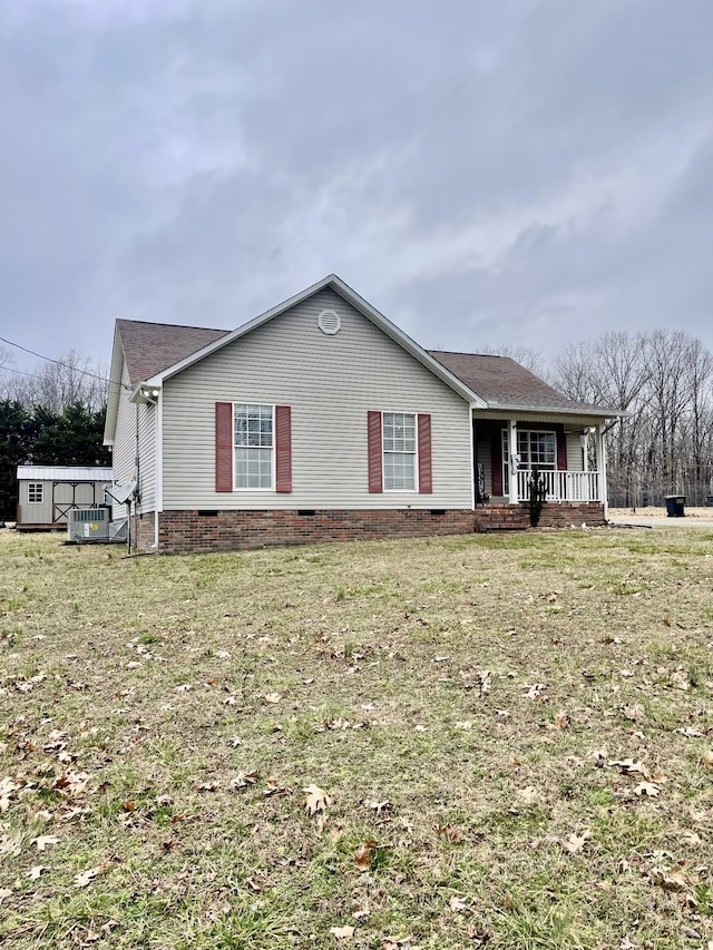 ranch-style home featuring a storage shed, a front lawn, and covered porch