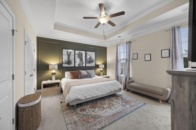 carpeted bedroom with a tray ceiling, ornamental molding, and ceiling fan