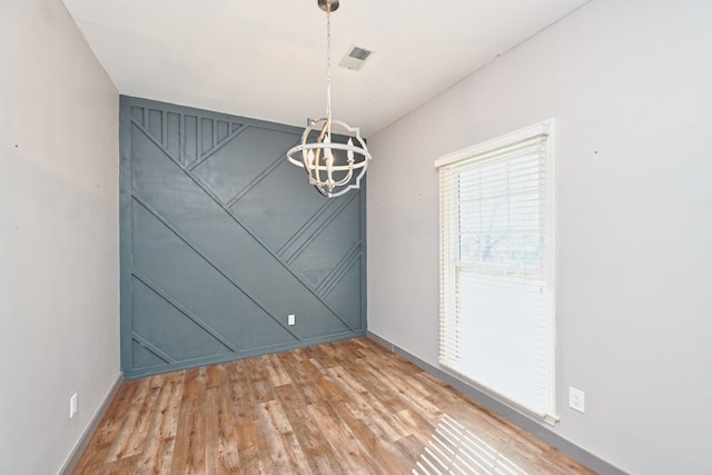 unfurnished dining area featuring hardwood / wood-style flooring and a notable chandelier