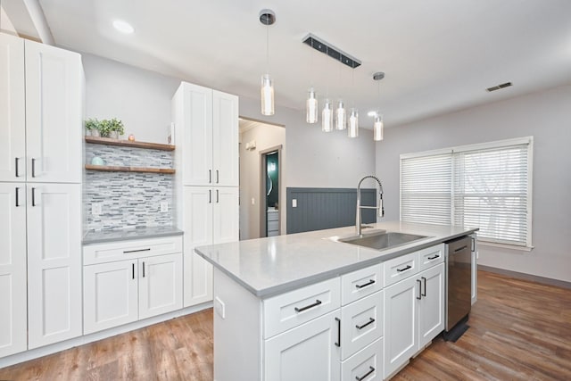 kitchen with decorative light fixtures, dishwasher, white cabinetry, sink, and a center island with sink