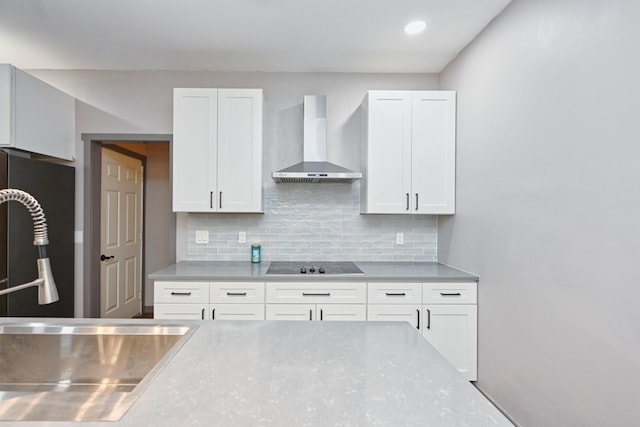 kitchen featuring sink, black electric stovetop, white cabinets, and wall chimney exhaust hood