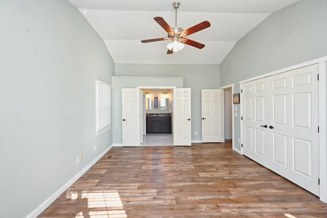 unfurnished bedroom featuring hardwood / wood-style floors, vaulted ceiling, a closet, and ensuite bathroom