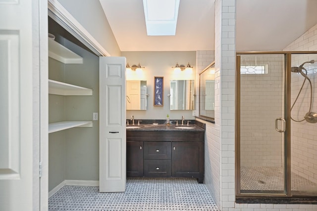 bathroom featuring vanity, a skylight, and a shower with door