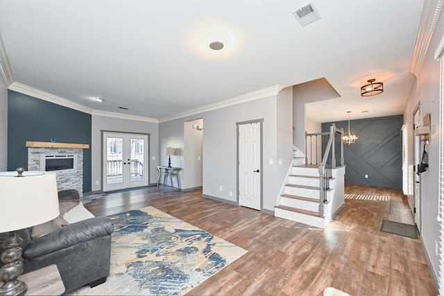 living room featuring french doors, a stone fireplace, hardwood / wood-style flooring, and a notable chandelier