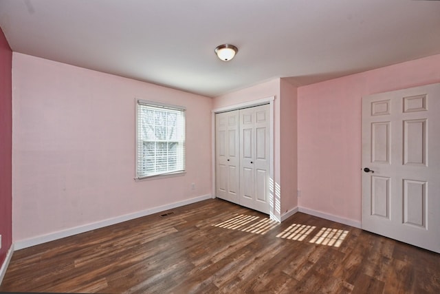 unfurnished bedroom with dark hardwood / wood-style floors and a closet