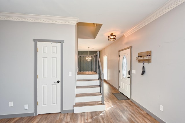 entrance foyer with crown molding, hardwood / wood-style floors, and a chandelier