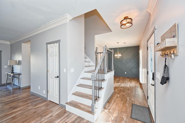 entrance foyer featuring an inviting chandelier, crown molding, and wood-type flooring