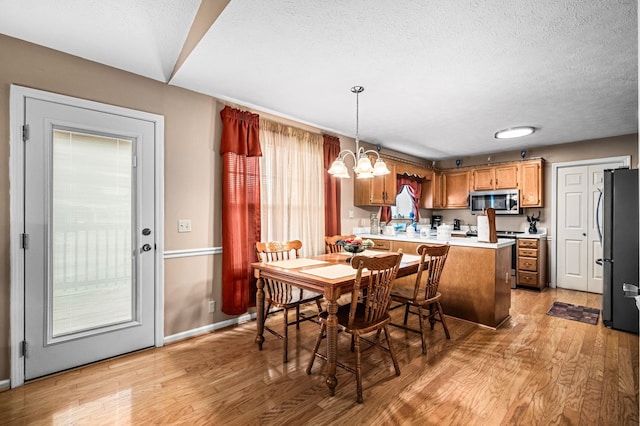 dining room with an inviting chandelier, light hardwood / wood-style floors, and a textured ceiling