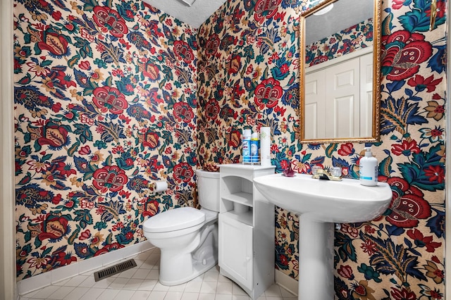 bathroom featuring tile patterned flooring, a textured ceiling, and toilet