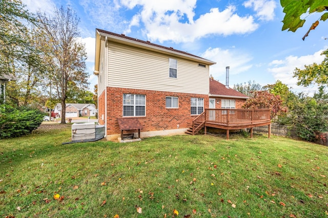 back of property with a wooden deck, a yard, and a jacuzzi