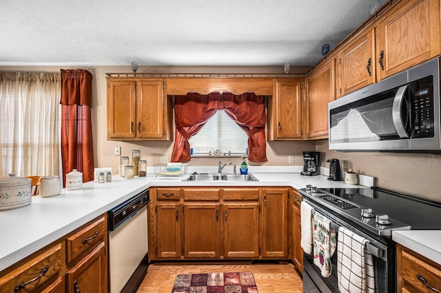 kitchen with appliances with stainless steel finishes, sink, and a textured ceiling