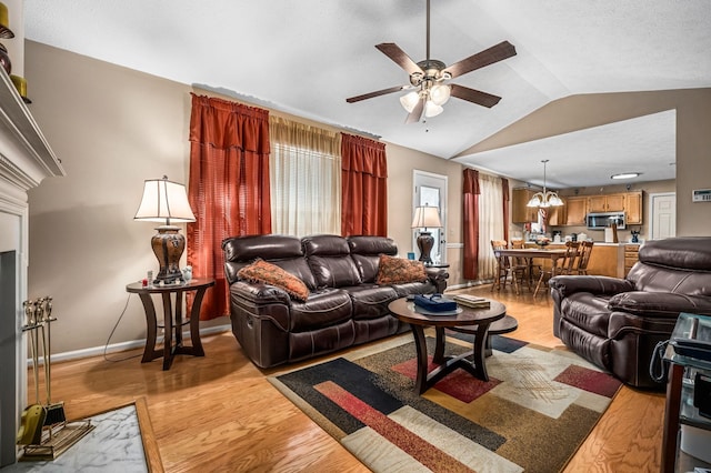 living room with vaulted ceiling, ceiling fan with notable chandelier, and light hardwood / wood-style flooring