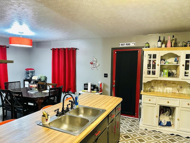 kitchen with butcher block countertops, sink, and a textured ceiling