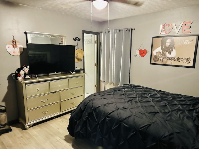 bedroom with ceiling fan, light wood-type flooring, and a textured ceiling