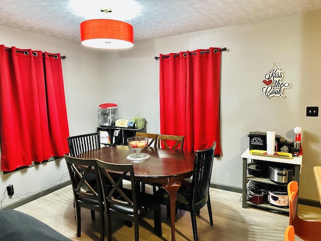 dining area featuring light wood-type flooring and a textured ceiling