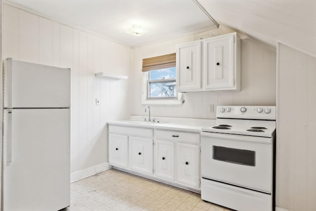 kitchen with sink, white appliances, white cabinetry, wooden walls, and vaulted ceiling