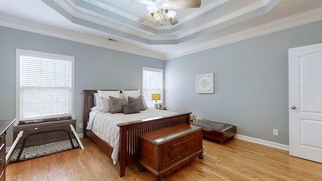 bedroom with crown molding, light hardwood / wood-style flooring, and a tray ceiling