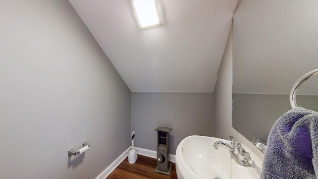 bathroom featuring lofted ceiling, sink, and hardwood / wood-style flooring