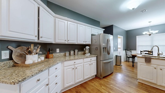 kitchen featuring sink, white cabinetry, stainless steel refrigerator with ice dispenser, light hardwood / wood-style floors, and decorative light fixtures