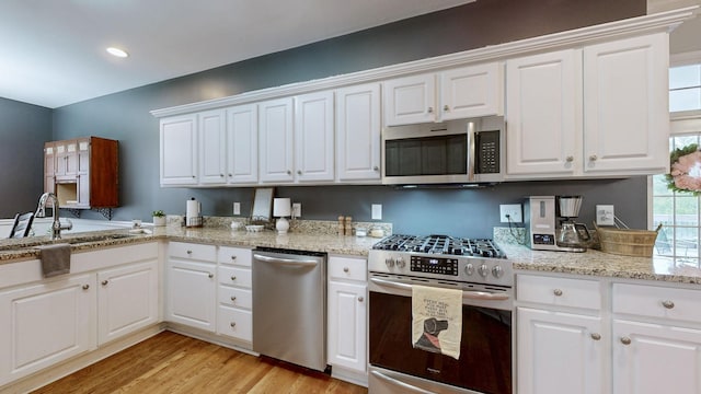 kitchen featuring appliances with stainless steel finishes, sink, light hardwood / wood-style flooring, and white cabinets