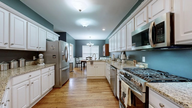 kitchen featuring decorative light fixtures, white cabinets, a chandelier, light hardwood / wood-style floors, and stainless steel appliances