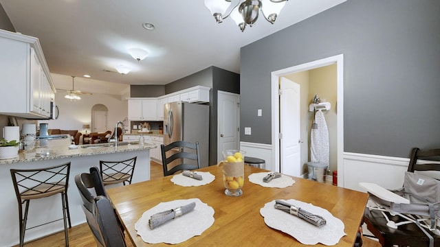 dining area with sink, ceiling fan with notable chandelier, and light hardwood / wood-style floors