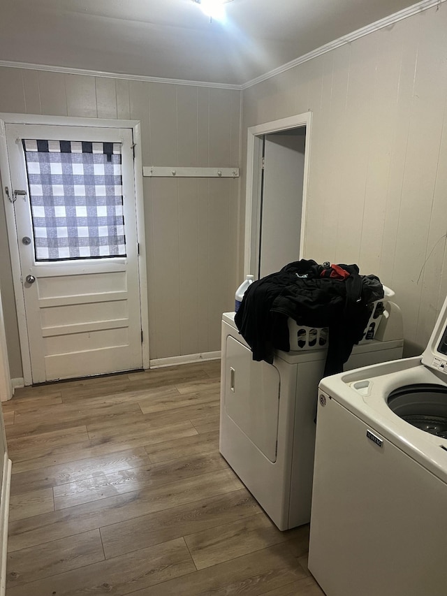 laundry room featuring ornamental molding, washing machine and dryer, and light wood-type flooring