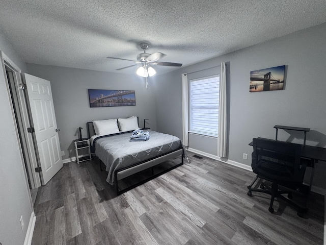 bedroom with a textured ceiling, dark wood-type flooring, and ceiling fan