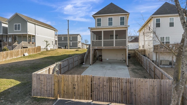 rear view of property featuring a garage, a lawn, and a sunroom