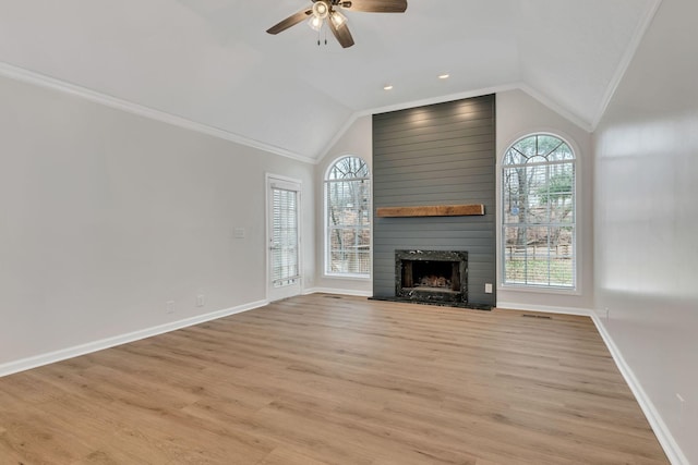 unfurnished living room with ornamental molding, lofted ceiling, a fireplace, and light hardwood / wood-style floors