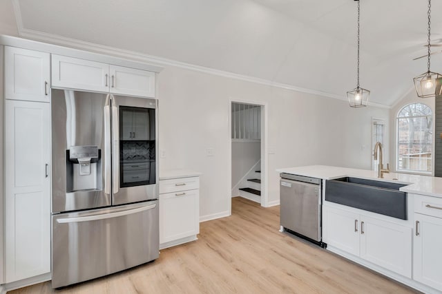 kitchen with stainless steel appliances, sink, white cabinets, and decorative light fixtures