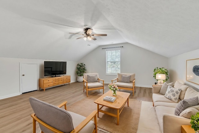 living room with ceiling fan, lofted ceiling, a textured ceiling, and light wood-type flooring