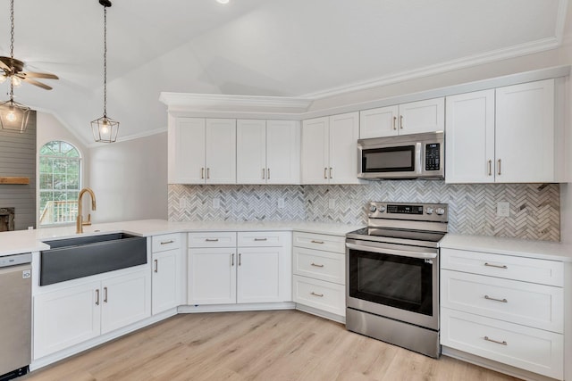 kitchen with pendant lighting, white cabinetry, lofted ceiling, sink, and stainless steel appliances