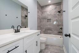 full bathroom featuring vanity, tiled shower / bath combo, and toilet