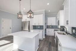 kitchen featuring stainless steel fridge, sink, a kitchen island, and white cabinets