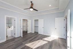 unfurnished bedroom with a tray ceiling, ornamental molding, and dark hardwood / wood-style floors