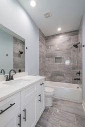 full bathroom with vanity, tiled shower / bath combo, and toilet