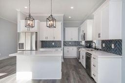 kitchen featuring a kitchen island, white cabinetry, appliances with stainless steel finishes, and pendant lighting