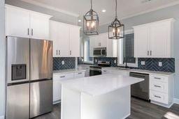 kitchen with decorative light fixtures, a kitchen island, white cabinets, and appliances with stainless steel finishes