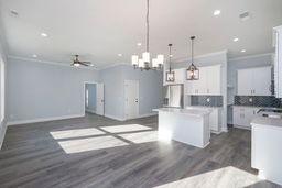 kitchen with pendant lighting, ornamental molding, a kitchen island, and white cabinets