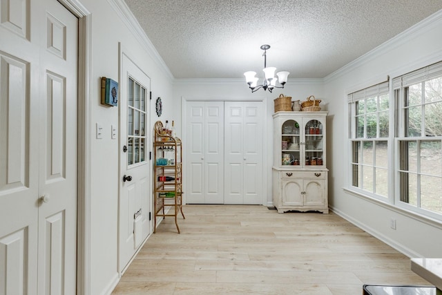 interior space featuring crown molding, a chandelier, light hardwood / wood-style flooring, and a textured ceiling