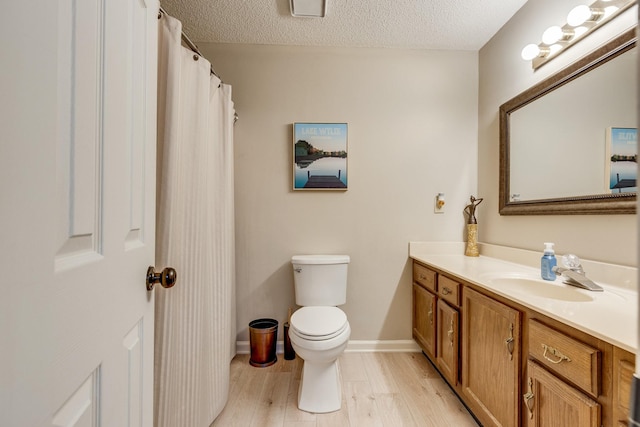 bathroom featuring vanity, hardwood / wood-style floors, toilet, and a textured ceiling