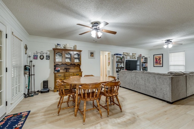 dining area featuring crown molding, ceiling fan, a textured ceiling, and light wood-type flooring