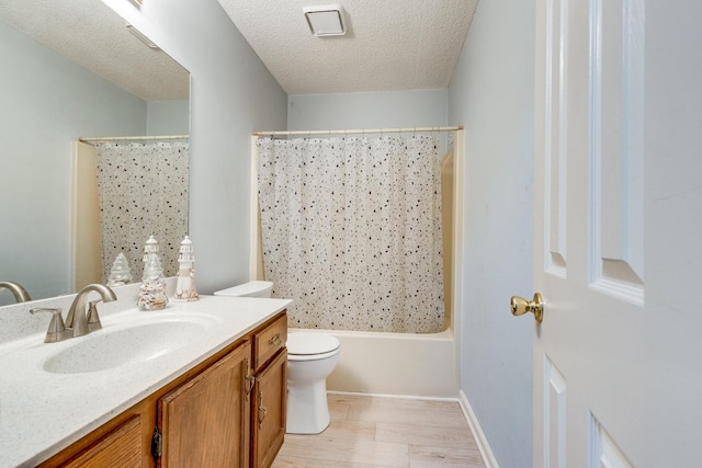 full bathroom featuring vanity, shower / tub combo with curtain, a textured ceiling, and toilet