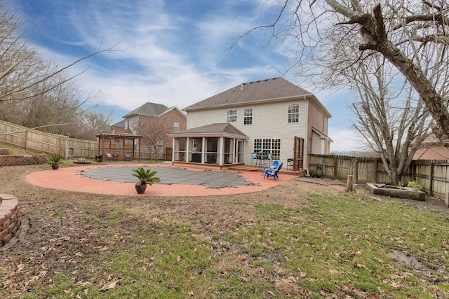 back of property with a patio area, a sunroom, and a lawn