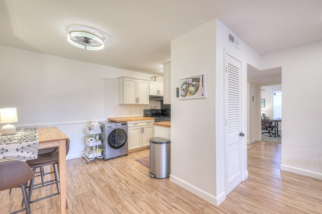 kitchen with wood counters, washer / clothes dryer, black electric range oven, and white cabinets