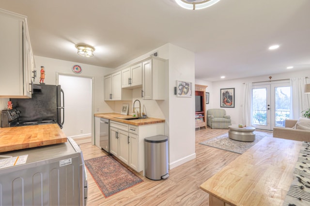 kitchen featuring sink, wooden counters, appliances with stainless steel finishes, light hardwood / wood-style floors, and french doors