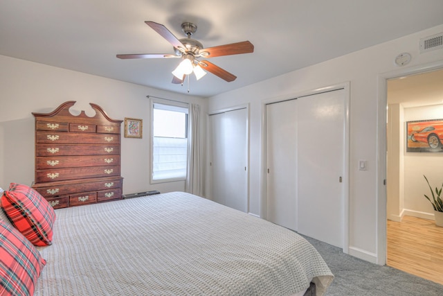 carpeted bedroom with multiple closets and ceiling fan