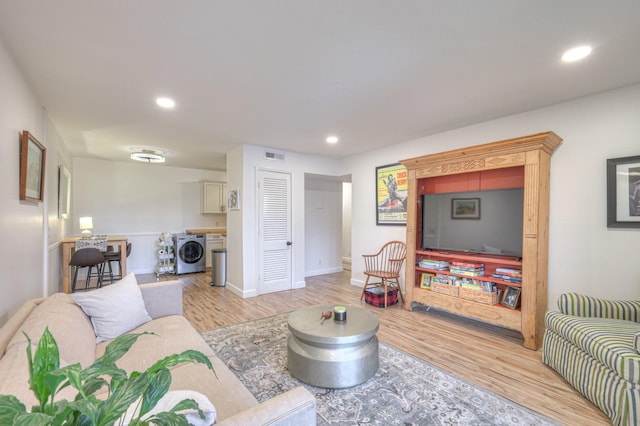 living room with washer / clothes dryer and light wood-type flooring